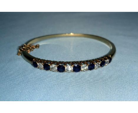 A late Victorian yellow metal hinged bangle set 6 graduating diamonds and 7 sapphires, total diamond weight 1.45 ct approx., 