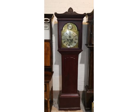 An 18th century stained pine longcase clock, with carved pediment to the hood, full length door, arched brass dial with silve