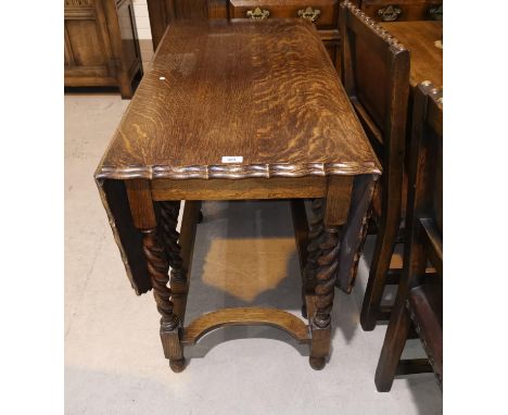 A 1930's golden oak drop leaf dining table, canted and scalloped on barley twist gate legs 