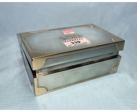 A hallmarked silver rectangular cigarette box with raised yellow metal mounts and monogram, hinged lid, on weighted base 