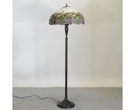 A modern black painted standard lamp, with a Tiffany style shade