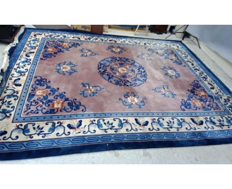 A CHINESE WASHED AND FRINGED CARPET, the dusky pink field with central floral gul in shades of blue, rust and ivory, surround