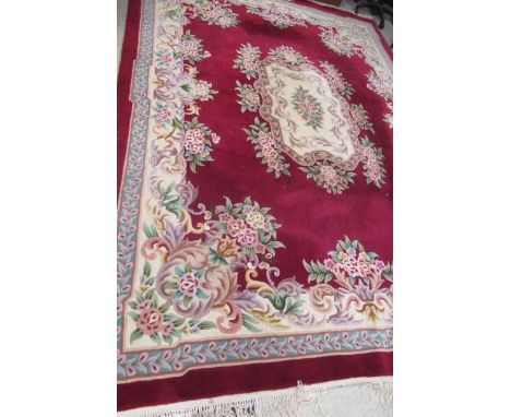 A CHINESE WASHED AND FRINGED CARPET, modern, the burgundy field with central floral gul in ivory, pink, turquoise and green w