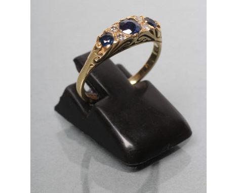 A VICTORIAN STYLE SAPPHIRE AND DIAMOND RING, the eliptical panel set with three mix cut sapphires with diamond chips between 