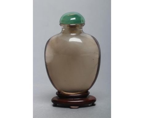 A CHINESE SMOKY CRYSTAL SNUFF BOTTLE, well hollowed out, 2 3/8" high, with domed jade(?) stopper and carved hardwood stand (I