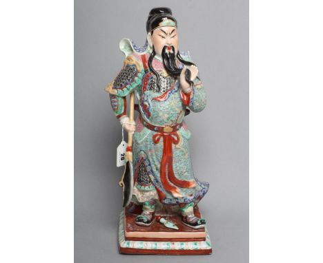 A CHINESE PORCELAIN FIGURE modelled as a celestial warrior wearing brightly coloured robes holding a spear and standing on a 