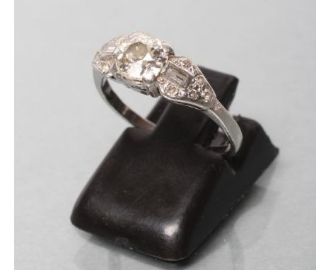 AN ART DECO DIAMOND RING, the brilliant cut centre stone claw set to shaped triangular shoulders point set with small diamond