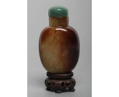 A CHINESE POLISHED OLIVE GREEN JADEITE SNUFF BOTTLE with amber/brown mottling, 2 1/4" high, with domed blue/green jade stoppe