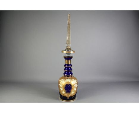 A Mid-20th Century Bohemian Blue Glass Decanter and Cover. The decanter of bottle form with ribbed collar, gold-coloured enam