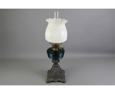 A Late Victorian Oil Lamp. The lamp supported on a cast metal base, with turquoise glass oil reservoir, white opaque glass gl