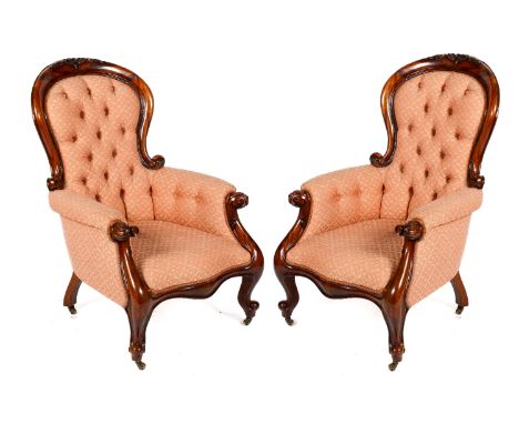 A pair of mahogany Victorian or later button back armchairs. Carved with scroll and flower details to the back and arms, with