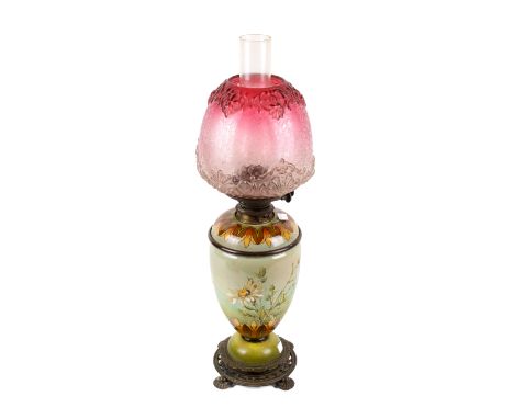 A circa 1890 faience oil lamp by Mary Butterton for Doulton Lambeth. Of ovoid urn form, the base painted with daisies on a gr