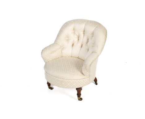 A circa 1900 button back nursing chair. Upholstered in cream fabric with diamond and leaf detail. Mahogany legs to brass cast