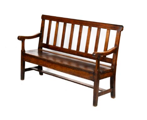 A long oak bench. With slatted back between chamfered top and side rails, over a single plank seat and squared supports. H98c