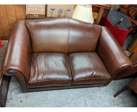 A Laura Ashley brown leather two person sofa, on turned forelegs 