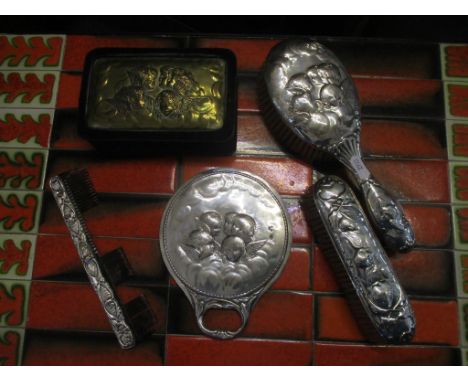 A silver dressing table set, each piece repousse decorated with winged heads, comprising a circular head mirror, two brushes 