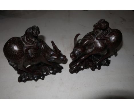 Pair of Chinese carved hardwood figures riding water buffalo with inlaid white metal detail and inset glass eyes (height 15cm