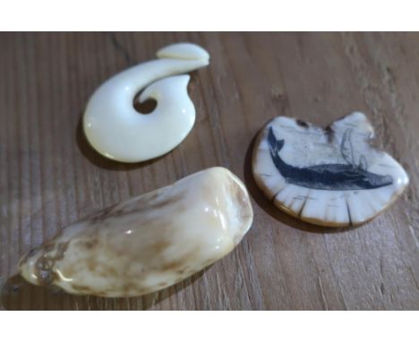 Three carved Inuit style marine ivory figures, one with engraved detail of a bird, another of a whale 