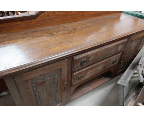 Large oak sideboard with raised back above two central drawers and open shelf, flanked by two carved and panelled doors (168c