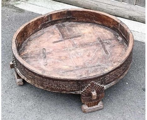 A large circular hardwood tribal trough, with a carved outline, 27cm high,79cm diameter 