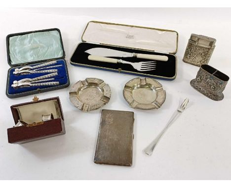 Two silver ash trays, a silver cigarette case, a silver pickle fork, a pair of silver napkins in a fitted case, 409.15g gross