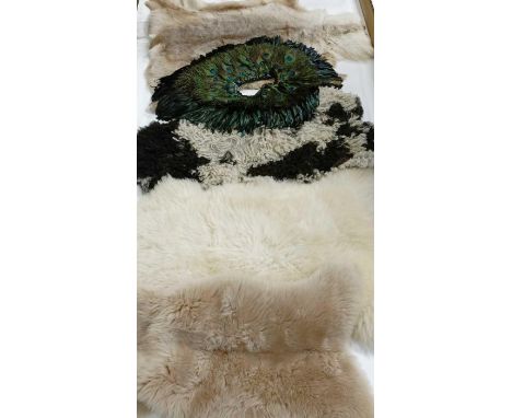 Three sheepskin rugs, along with a deer skin rug and a peacock shrug