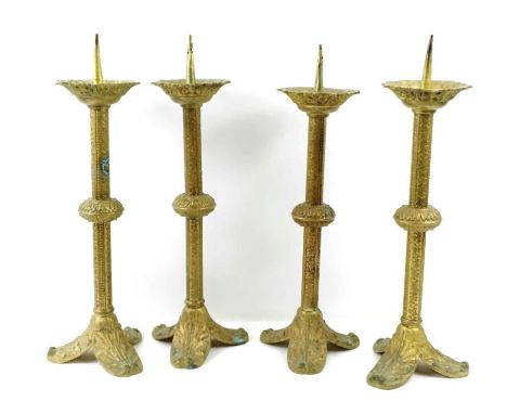 A set of four brass church candlesticks, each standing on a tripod base