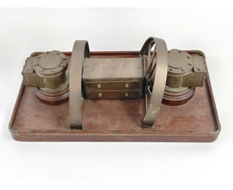 A unusual trench art style inkwell, standing on a mahogany base, 12cm high, 38cm long, 23cm wide