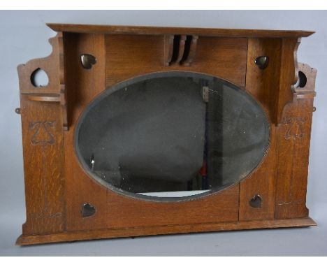 AN ARTS & CRAFTS OAK OVERMANTEL MIRROR, the overhanging cornice supported on two corner shelf brackets and central shaped mou