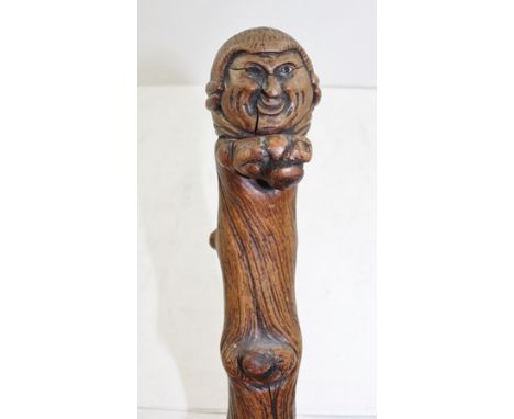 A CARVED CRABSTOCK WALKING STICK, the gnarled stem with carved mask knob handle, in the form of a be-wigged gentleman, 95cm h