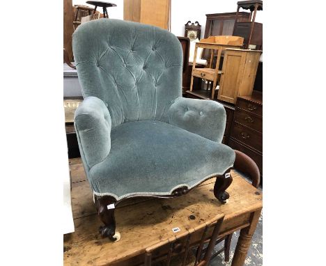 A late Victorian rosewood button upholstered armchair, the front legs on white ceramic caster feet