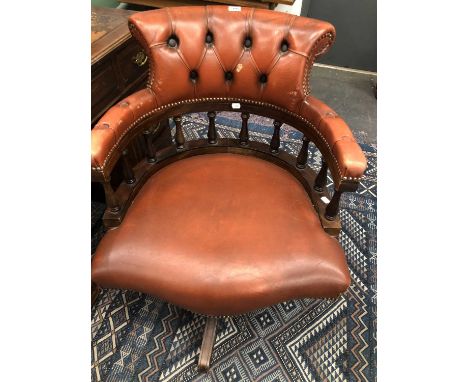 A button upholstered leather desk chair rotating on four mahogany legs on caster feet