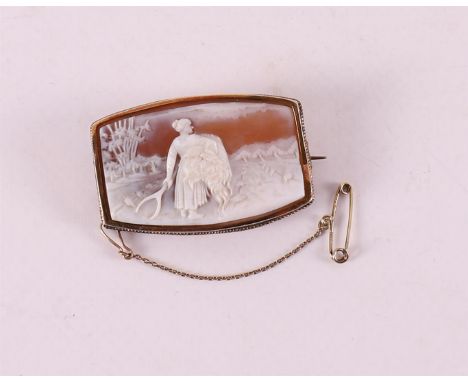 A 14 krt 585/1000 gold frame with shell cameo depicting a farmer's wife in a landscape with fork and bale of hay, circa 1900.