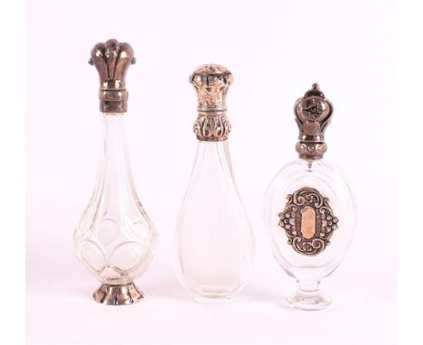 A clear crystal odeur flask with silver flip lid and frame, 19th C., including stopper, h12 cm. Hereby two others with silver