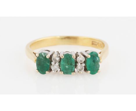 An emerald and diamond ring, set with three oval cut emeralds, interspersed with round brilliant cut diamond accents, stamped