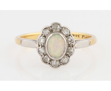 An opal and diamond cluster ring, set with a central oval opal cabochon, measuring approx. 6x4mm, surrounded by a border of t