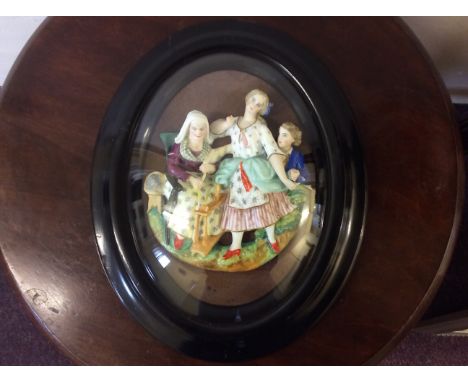 A black framed ceramic painted figure relief group.