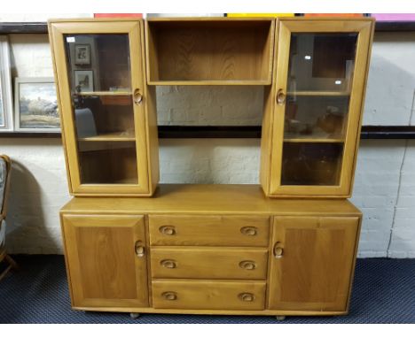 An Ercol light elm low sideboard, fitted three drawers, two doors with raised glazed cabinet back.