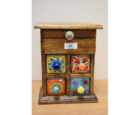 An unusual hardwood and ceramic miniature set of drawers, for jewellery and trinkets, with four colourful ceramic drawers in 