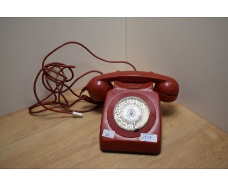 A vintage red rotary telephone.