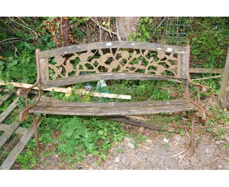 A garden bench having a slatted seat and cast iron back and ends, in need of attention.