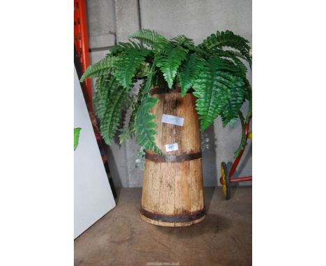 An artificial fern in a wooden planter.