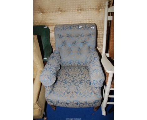 A blue upholstered, button back armchair.