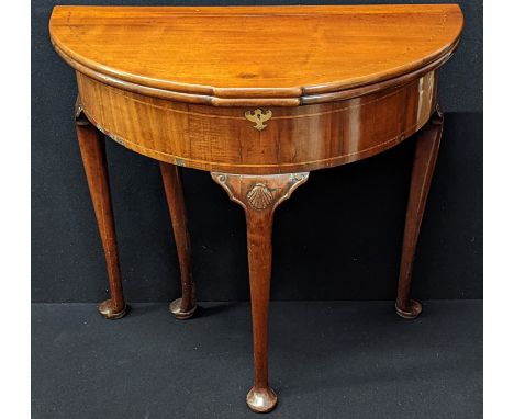 A George II mahogany demi lune tea table, double fold top, a band of marquetry inlay to frieze, moulded shell decor to middle