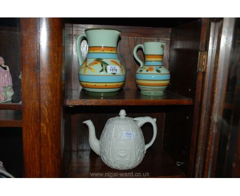 A Parian teapot and two Jugs in pale green with blue, yellow and orange bands and similar floral decoration