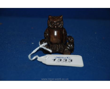 A reproduction dark wood Japanese netsuke of an owl on a branch, signed