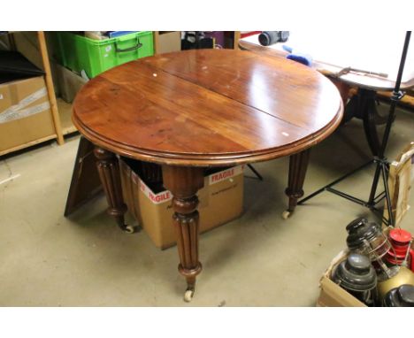 19th century Mahogany Oval Wind-out Dining Table with one additional leaf, raised on turned reeded legs terminating in cerami