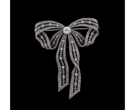 An Edwardian diamond and platinum bow brooch/pendant, circa 1910, set with a central old cut diamond estimated to weigh 1.17 