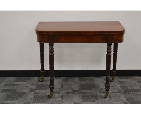 An early 20th century mahogany card/games table,  lift open top with green baize, the back legs move out, raised on turned su