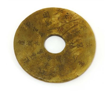 A Chinese jade bi disc, Qing dynasty (1644-1911), incised with a poem, the stone of brown tone, 6.9cm diameter